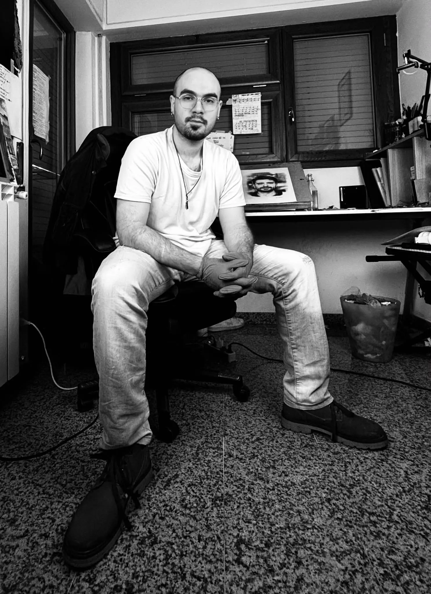 Giorgio Luppino seduto nel suo studio, circondato dai disegni.